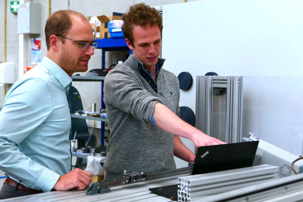 Ein Photo, auf dem zwei HCP Sense Mitgründer die Ergebnisse der Analyse der Lagerkräfte, die auf einem Rechner dargestellt sind, besprechen